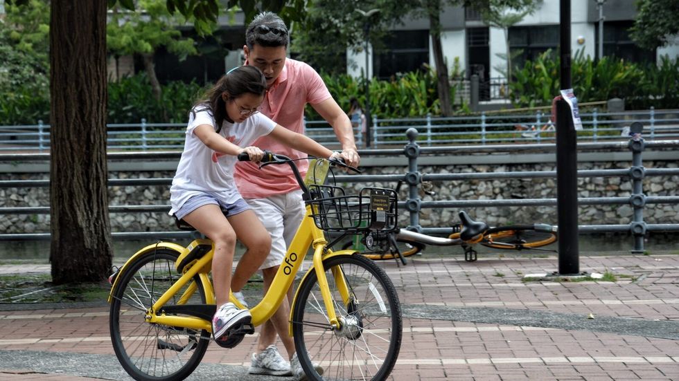 man teaching a little girl to ride a bike