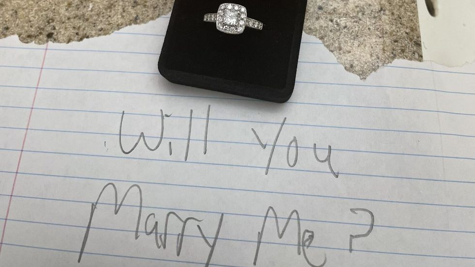 a ring in a box and a note that says "will you marry me"