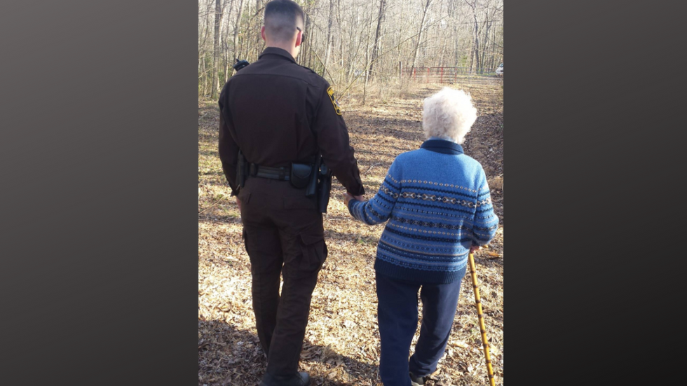 police officer and elderly woman holding hands