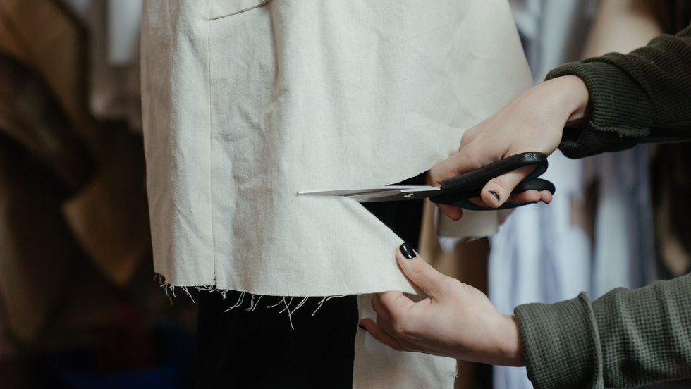 person cutting cloth with scissors