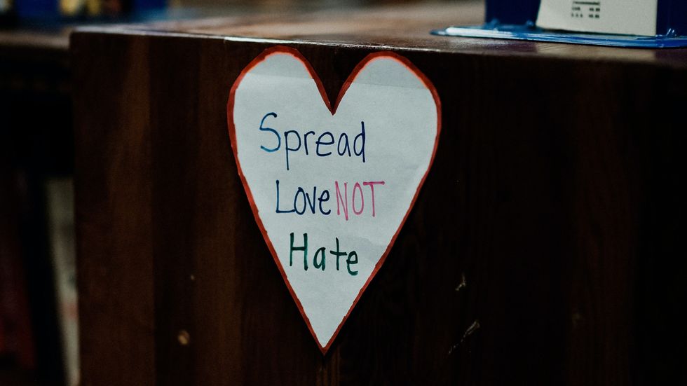 "spread love not hate" written in a paper heart