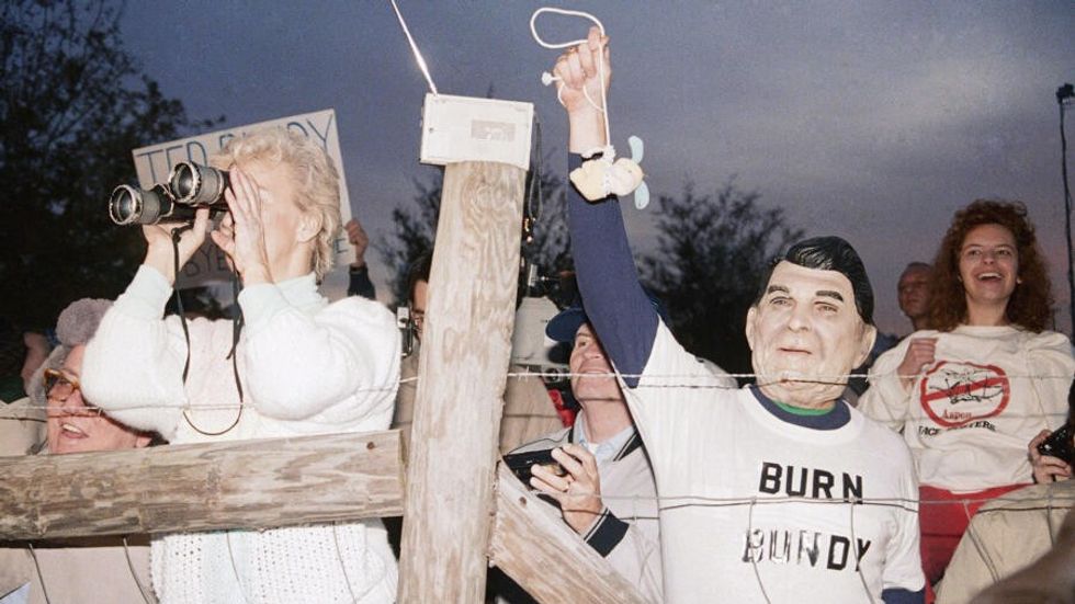 A toy bunny is hung in effigy by Jerry Jackson of Atlanta, Georgia, wearing a Ronald Reagan mask, and the pro-death penalty crowd rejoices after the Ted Bundy execution