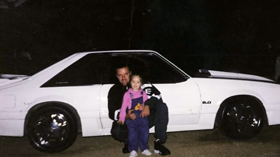 man with a little girl in front of a white car