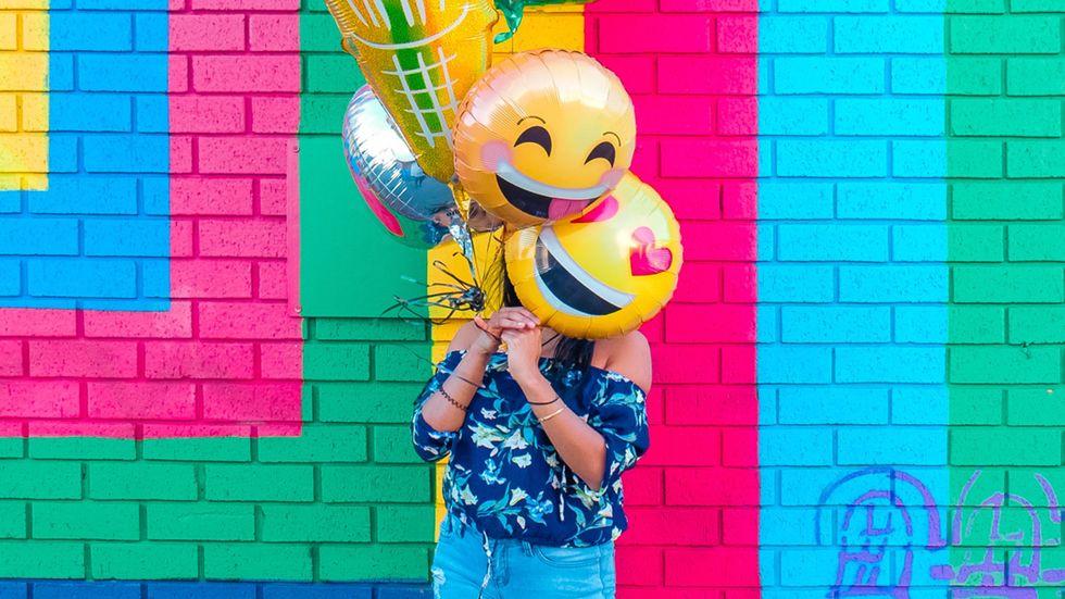 woman holding up smiley balloons
