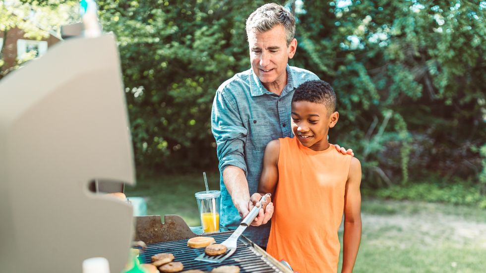 man and little boy grilling burgers outside