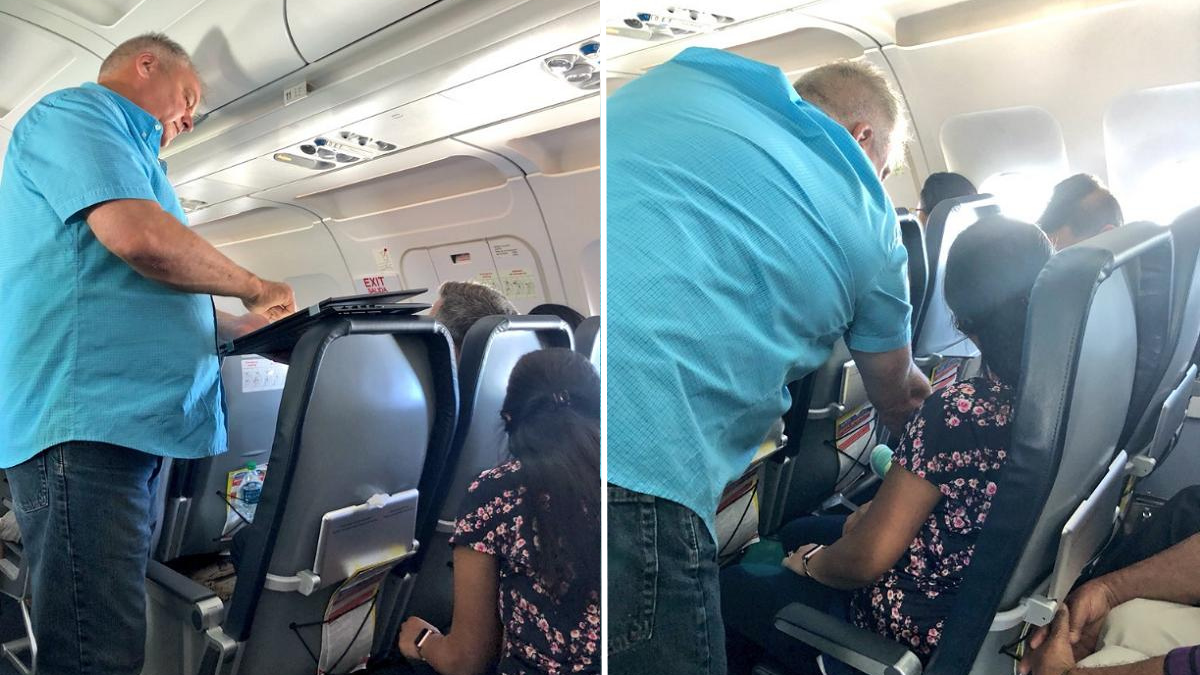 man in a blue shirt talking to passengers on a flight