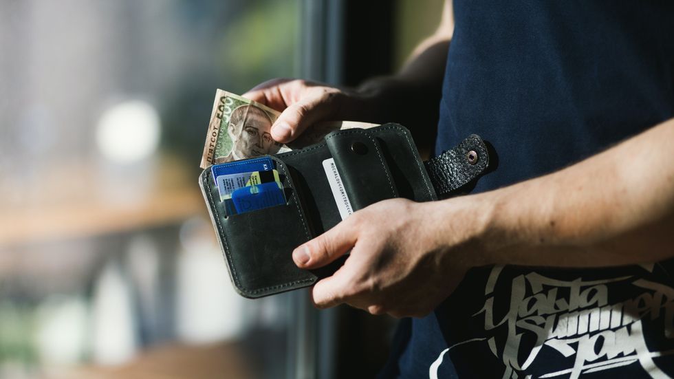 person holding a black wallet with money
