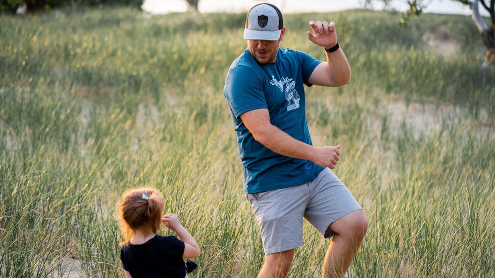 man dancing with his little daughter in a field