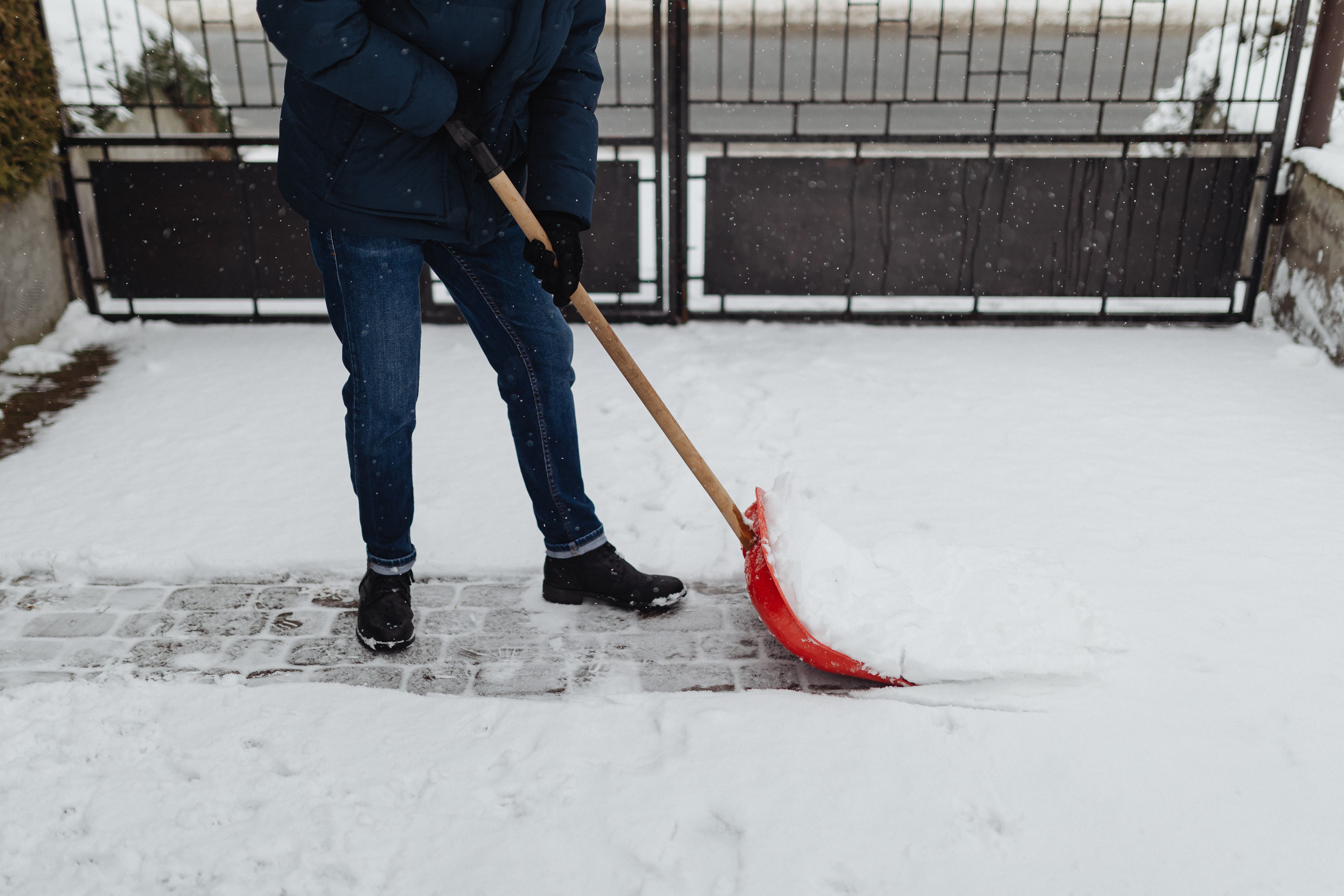 person in a winter jacket shoveling snow