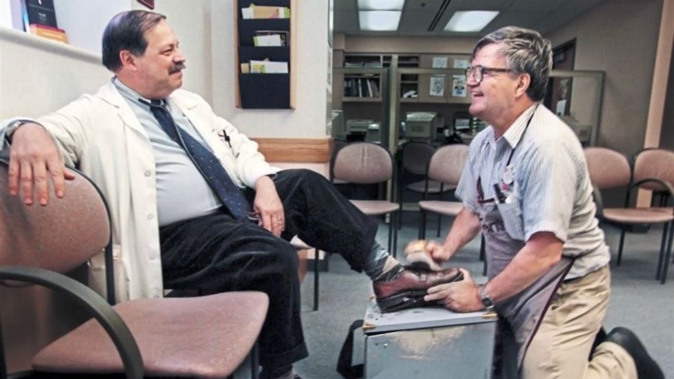 elderly man shining a man's shoes