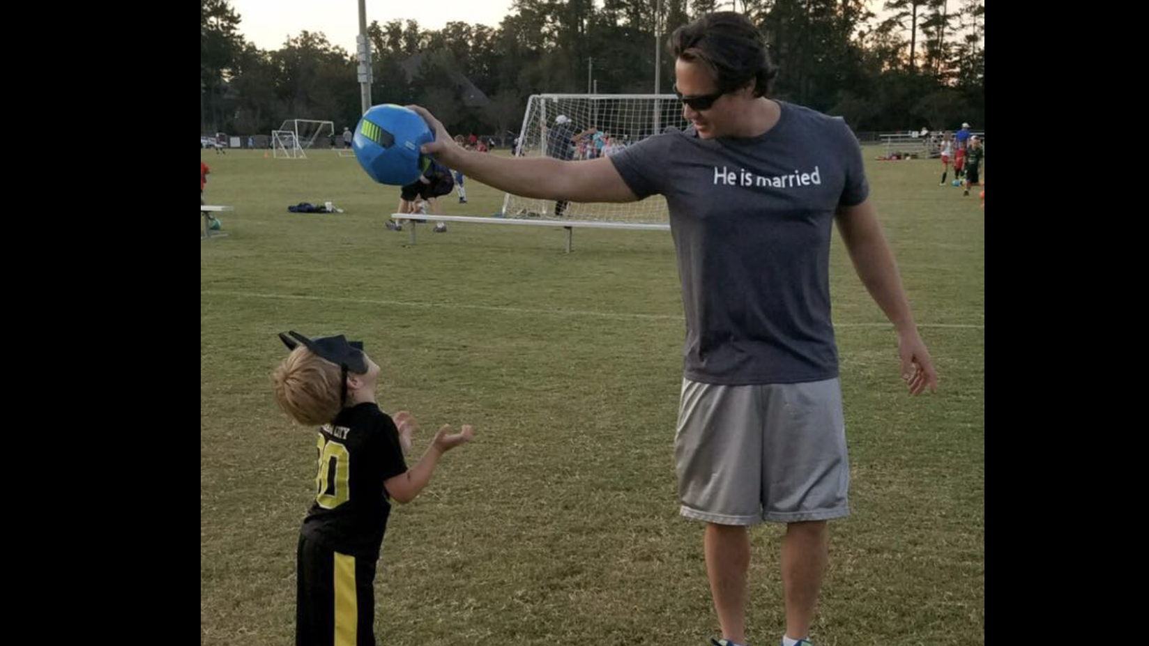 man holding a ball over a little kid's head