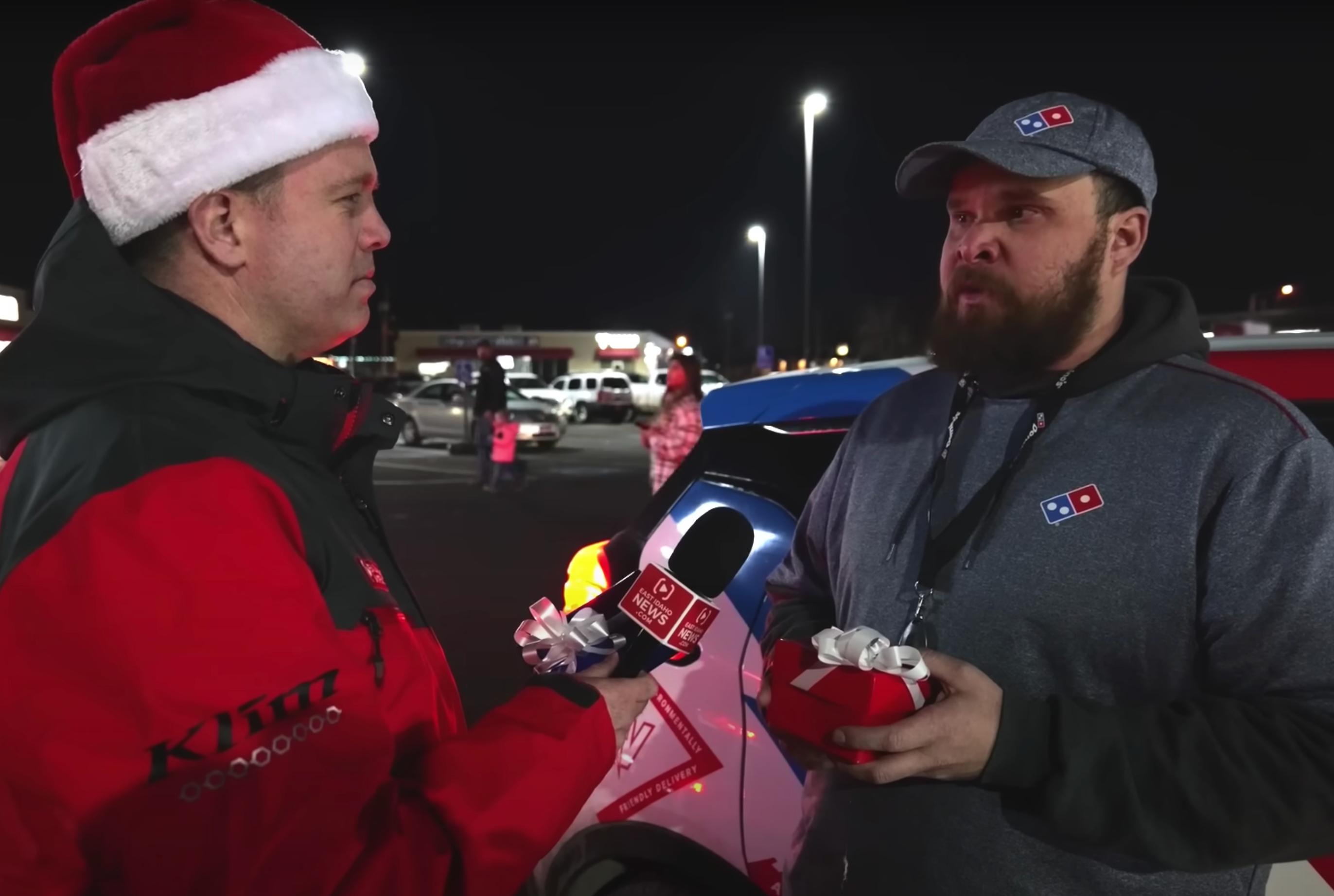 man wearing a Santa hat talking to a man with a beard